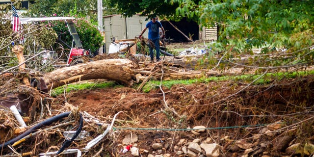 A man clears debris on property along the East Fork Pigeon River in Cruso, N.C., Friday, Aug. 20, 2021, after remnants from Tropical Storm Fred caused flooding in parts of Western North Carolina on Tuesday.