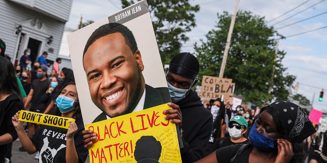A protester holds a sign for Botham Jean during a march at a protest on June 9, 2020, in Revere, Massachusetts.  (Getty Images)