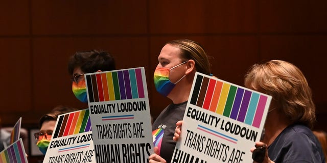 ASHBURN, VA - AUGUST 11: Supporters of Policy 8040 celebrate with signs as the transgender protection measures were voted into the school systems policies during a school board meeting at the Loudoun County Public Schools Administration Building on August 11, 2021 in Ashburn, Va. (Photo by Ricky Carioti/The Washington Post via Getty Images)