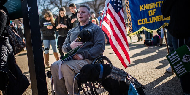 Iraq and Afghanistan veteran Kirby Bowling, 45, of Laurel, MD, is photographed along his dog Sig, during the national anthem at the 45th annual March for Life, "Love Saves Lives," at the National Mall in Washington, D.C. 