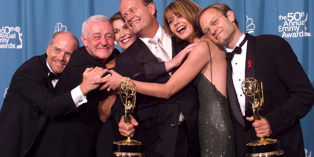 Emmy-winners, actors Kelsey Grammer (center) and David Hyde Pierce (R) are joined by fellow 'Frasier' cast members actors Jane Leeves (2nd R), Peri Gilpin, John Mahoney (2nd L) and James Burrows (L) for a group-hug backstage at the 50th Annual Emmy Awards, on September 13, 1998 in Los Angeles, California.