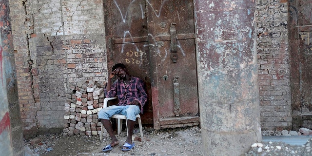 A man sits in front of a damaged building in Jeremie, Haiti, miércoles, ago. 18, 2021, four days after the city was struck by a 7.2-magnitude earthquake. (AP Photo/Matias Delacroix)