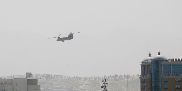 A US Chinook helicopter flies near the US Embassy, left, in Kabul, Afghanistan, Sunday, August 15, 2021 (Associated Press)