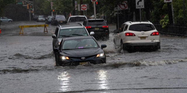 Car pass by a flooded street as Tropical Storm Henri approaches, in Hoboken New Jersey on August 22, 2021.