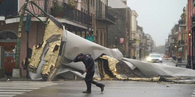 A man passes by a section of roof that was blown off of a building in the French Quarter by Hurricane Ida winds, Sunday, Aug. 29, 2021, in New Orleans. 