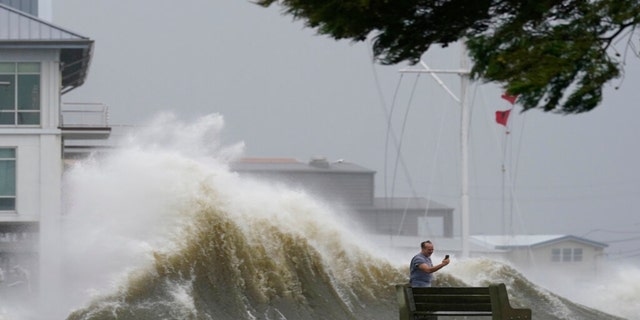 A man takes pictures of high waves along the shore of Lake Pontchartrain as Hurricane Ida nears, Sunday, Aug. 29, 2021, in New Orleans.