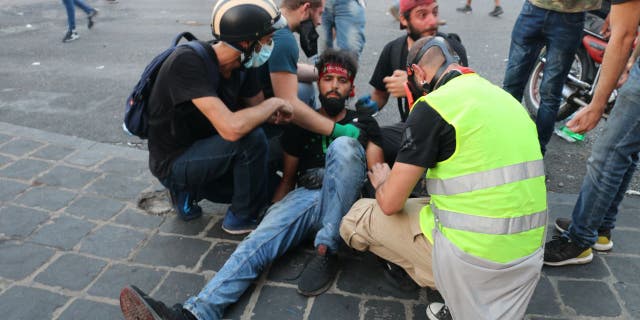 Protesters attend to an injured man during protests on the anniversary of a massive explosion in Beirut.