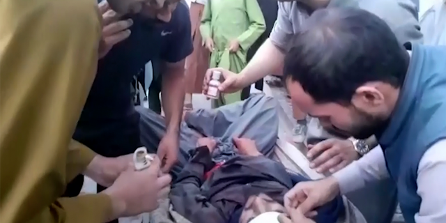 In this frame grab from video, people attend to a wounded man near the site of a deadly explosion outside the airport in Kabul, 阿富汗, 星期四, 八月. 26, 2021. Two suicide bombers and gunmen have targeted crowds massing near the Kabul airport, in the waning days of a massive airlift that has drawn thousands of people seeking to flee the Taliban takeover of Afghanistan. (美联社照片)