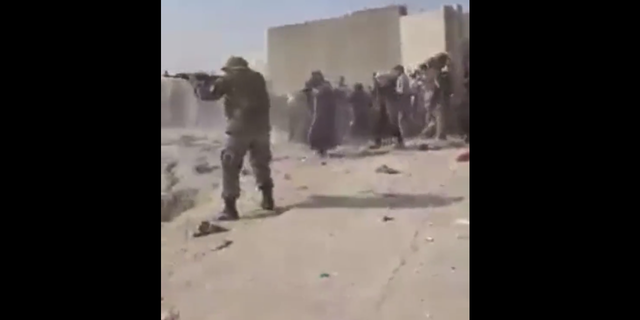 People take cover near Kabul's airport as guns are fired Thursday.