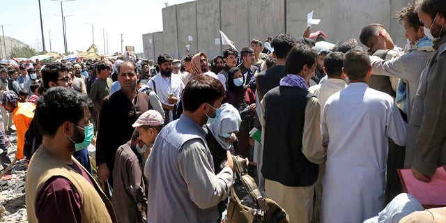 Hundreds of people, some holding documents, gather near an evacuation control checkpoint on the perimeter of Hamid Karzai International Airport in Kabul, Afghanistan, on Aug. 26, 2021.