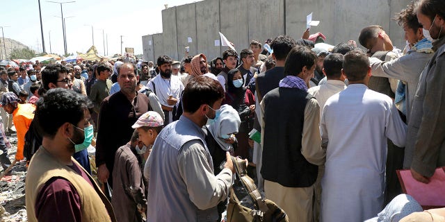 Hundreds of people, some holding documents, gather near evacuation control checkpoints around Hamid Karzai International Airport in Kabul, Afghanistan, August 26, 2021.