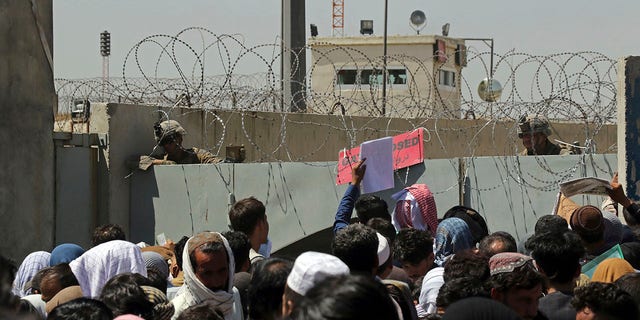 U.S. soldiers stand inside the airport as hundreds of people gather near an evacuation control checkpoint on the perimeter of the Hamid Karzai International Airport, in Kabul, Afghanistan, Aug. 26, 2021. 