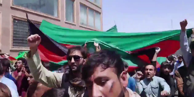 Demonstrators are seen marching in Kabul on Thursday, waving the Afghanistan flag. 