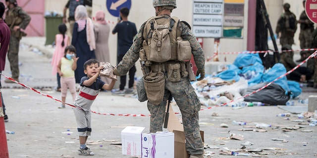 In this Aug. 20, 2021, photo provided by the U.S. Marine Corps, a Marine with the 24th Marine Expeditionary Unit (MEU) provides a meal ready-to-eat to a child during an evacuation at Hamid Karzai International Airport in Kabul, Afghanistan. 