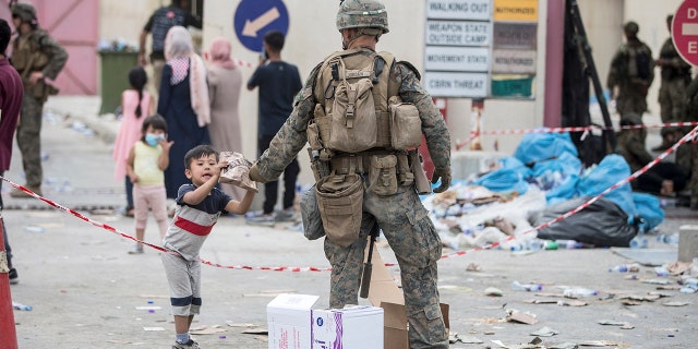 In this Aug. 20, 2021, photo provided by the U.S. Marine Corps, a Marine with the 24th Marine Expeditionary Unit (MEU) provides a meal ready-to-eat to a child during an evacuation at Hamid Karzai International Airport in Kabul, Afghanistan.