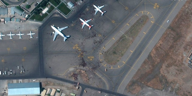 This satellite photo from Maxar Technologies shows swarms of people on the tarmac at Kabul International Airport on Monday. (AP/Maxar Technologies)