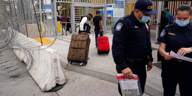 FILE: Honduran Alex Cortillo, left, and his stepbrother pull their suitcases to the border crossing into the U.S. to begin the asylum process, in Tijuana, Mexico.