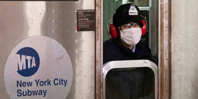 FILE — In this April 18, 2020 file photo, a subway conductor wears a face mask as the train is in a station, in the Bronx borough of New York. New York Gov. Andrew Cuomo and New York City Mayor Bill de Blasio have scheduled competing news conferences Monday, Aug. 2, 2021, amid rising COVID-19 case counts attributed to the highly contagious delta variant of the virus. (AP Photo/Mark Lennihan, File)