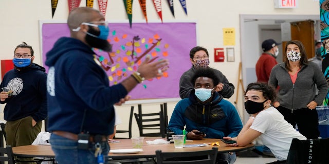 Students, teachers, administrators and counselors listen as principal Malik Lewis, second from left, teaches them a history lesson at West Brooklyn Community High School in New York in October 2020. (AP)