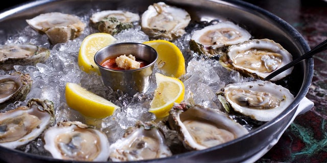 A dozen raw oysters on a plate at a restaurant.