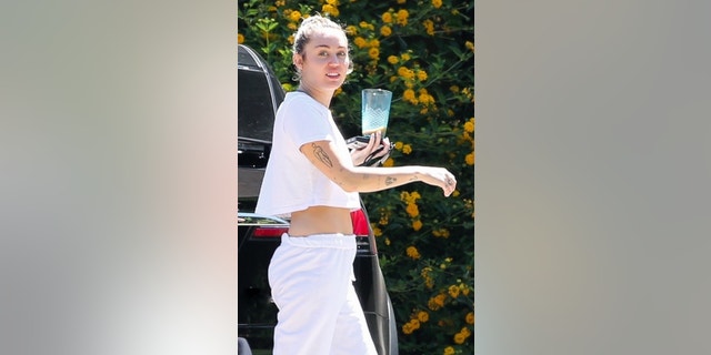 A makeup-free Miley Cyrus keeps it simple and comfy by wearing sweatpants and a white cropped top and loafers while visiting friends in Malibu.  The singer was seen getting out of her car and bringing a drink with her as she made her way home.