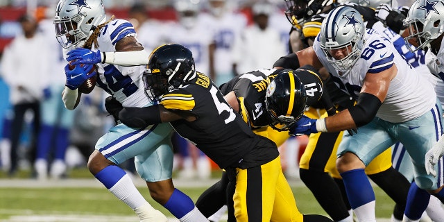 Dallas Cowboys running back Rico Dowdle (34) tries to escape the grasp of Pittsburgh Steelers linebacker Ulysees Gilbert III during the first half of the Pro Football Hall of Fame NFL preseason game Thursday, Aug. 5, 2021, in Canton, Ohio. (Associated Press)