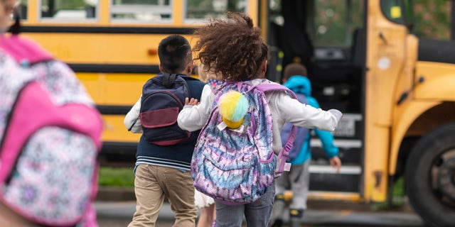 School children board a bus.