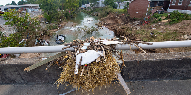 Debris captured atop a bridge shows how high the waters reached when cars were washed into the creek after recent flooding on Monday, August 23, 2021, in Waverly, Tennessee.  Heavy rains caused flooding in central Tennessee days earlier and killed several people.  , and missing people as homes and rural roads were also washed away. 