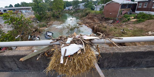 Debris caught on top of a bridge shows how high water reached as cars washed into the creek after recent flooding, Monday, Aug. 23, 2021, in Waverly, Tenn. Heavy rains caused flooding in Middle Tennessee days earlier and have resulted in multiple deaths, and missing people as homes and rural roads were also washed away.