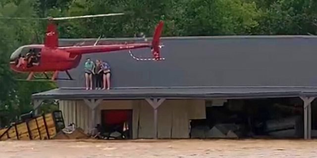 This image from video provided by Jeani Rice-Cranford shows Nashville-based helicopter pilot Joel Boyers rescuing people from a rooftop, Saturday, Aug. 21, 2021 in Waverly, Tenn. Boyers, who co-owns Helistar Aviation, said he ended up rescuing 17 people that day. He’s proud of that, but said he’s the one who should be thanking them.