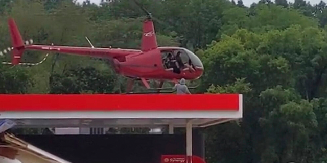 Esta imagen del video proporcionada por Jeani Rice-Cranford muestra al piloto de helicóptero Joel Boyers rescatando a personas de un tejado el sábado 21 de agosto de 2021 en Waverly, Tennessee.  Boyers, copropietario de Helistar Aviation, dijo que terminó salvando a 17 personas ese día.  Está orgulloso de ellos, pero dice que es él quien debería agradecerles. 