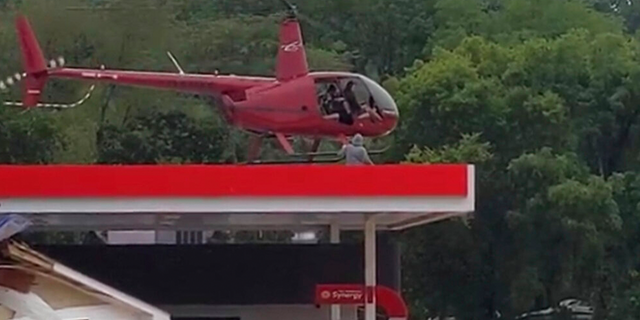 Esta imagen del video proporcionada por Jeani Rice-Cranford muestra al piloto de helicóptero Joel Boyers rescatando a personas de un tejado el sábado 21 de agosto de 2021 en Waverly, Tennessee.  Boyers, copropietario de Helistar Aviation, dijo que terminó salvando a 17 personas ese día.  Está orgulloso de ellos, pero dice que es él quien debería agradecerles. 