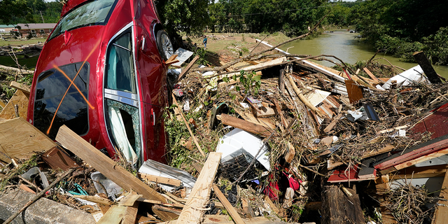 A car is among debris that washed up against a bridge over a stream Sunday, Aug. 22, 2021, in Waverly, Tenn. Heavy rains caused flooding Saturday in Middle Tennessee and have resulted in multiple deaths as homes and rural roads were washed away. 