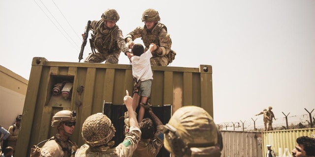 In this photo provided by the Department of Defense, American troops are shown helping people to safety.
