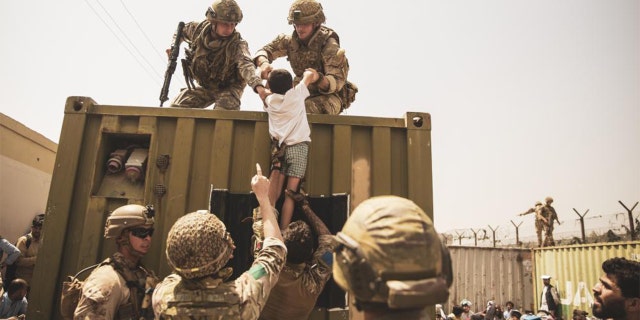 In this photo provided by the Department of Defense, American troops are shown helping people to safety.