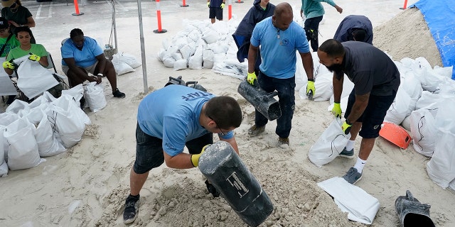 City workers fill sandbags at a drive-thru sandbag distribution event for residents ahead of the arrival of rains associated with tropical depression Fred, Friday, Aug. 13, 2021, at Grapeland Park in Miami. (AP Photo/Wilfredo Lee)