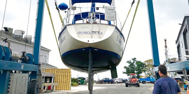 A marina worker watches as a sailboat is hauled out of the water onto dry land in advance of an expected storm, Friday Aug. 20, 2021, in Plymouth, Mass. New Englanders, bracing for their first direct hit by a hurricane in 30 years, are taking precautions as Tropical Storm Henri barrels toward the southern New England coast.