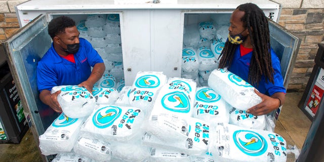 Corey Williams, right, and John Smith, both of Pelican Ice, hurriedly stack bags of ice into a gas station freezer in preparation for Tropical Storm Ida on Friday, Aug.  27, 2021 in Jefferson, La.  Forecasters now say Ida could be a major Category 3 hurricane with top winds of 115 mph when it nears the U.S. coast. 