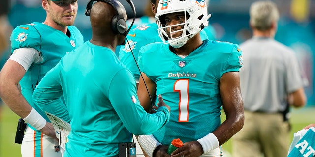 El mariscal de campo de los Miami Dolphins, Dua Takovilova (1), habla con el entrenador en jefe Brian Flores en la primera mitad del partido de pretemporada de la NFL contra los Atlanta Falcons el sábado 21 de agosto de 2021 en Miami Gardens in Flow.