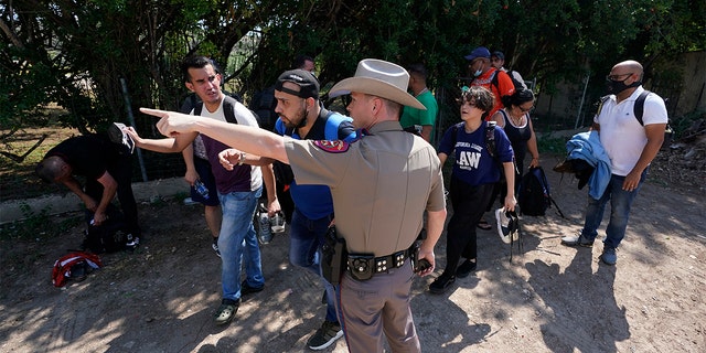 June 16, 2021: A Texas Department of Public Safety officer in Del Rio, Texas directs a group of migrants who crossed the border and turned themselves in. (AP Photo/Eric Gay, File)