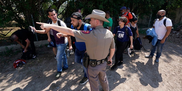 A Texas Department of Public Safety officer in Del Rio, Texas directs a group of migrants who crossed the border and turned themselves on June 16, 2021.