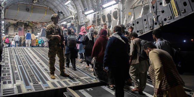 Afghan passengers board a U.S. Air Force C-17 Globemaster III during the Afghanistan evacuation at Hamid Karzai International Airport in Kabul, Afghanistan.