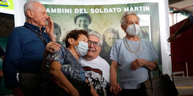 A 97 year old retired American soldier Martin Adler poses with Giulio, left, Mafalda, right, and Giuliana Naldi that he saved during a WWII at Bologna's airport, Italy, Monday, Aug. 23, 2021. For more than seven decades, Martin Adler treasured a back-and-white photo of himself as a young soldier with a broad smile with three impeccably dressed Italian children he is credited with saving as the Nazis retreated northward in 1944. The 97-year-old World War II veteran met the three siblings -- now octogenarians themselves -- in person for the first time on Monday, eight months after a video reunion. 