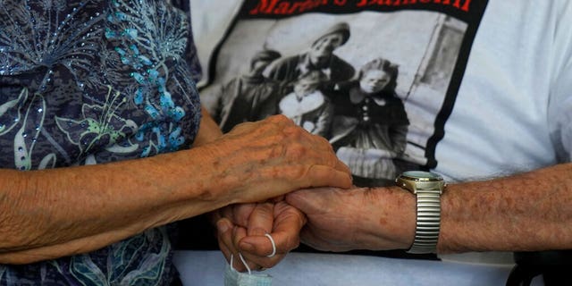 A 97 year old retired American soldier Martin Adler holds Giuliana Naldi's hand that he saved during a WWII, at Bologna's airport, Italy, Monday, Aug. 23, 2021. For more than seven decades, Martin Adler treasured a back-and-white photo of himself as a young soldier with a broad smile with three impeccably dressed Italian children he is credited with saving as the Nazis retreated northward in 1944. The 97-year-old World War II veteran met the three siblings -- now octogenarians themselves -- in person for the first time on Monday, eight months after a video reunion. 