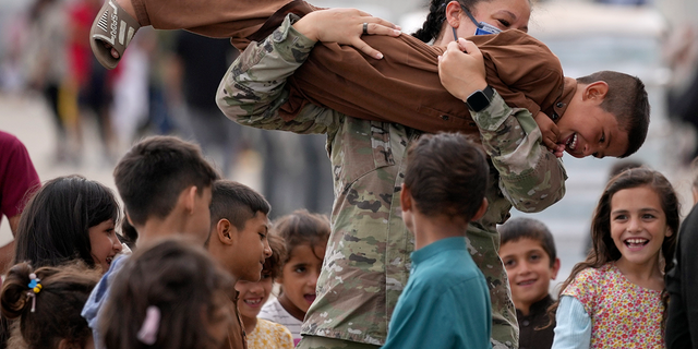 An U.S. soldier plays with recently evacuated Afghan children. 