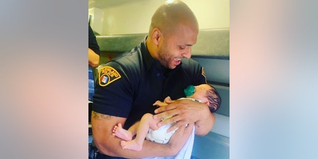 Cleveland Police Patrol Officer Hassan Ali is pictured holding 6-week-old Cannon Tatum McDoodle after the child was found safe Wednesday.
