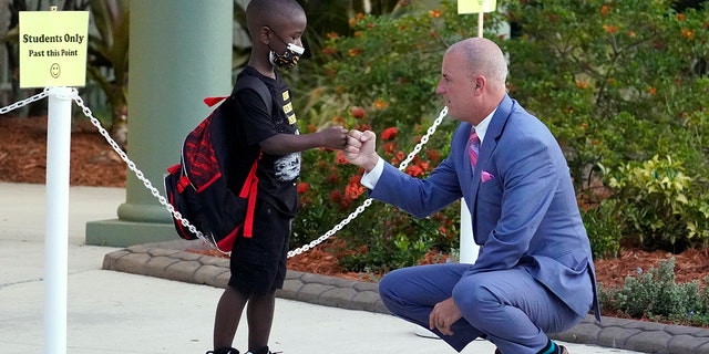 Addison Davis, Hillsborough County Superintendent of Schools, right, fist bumps student James Braden before he heads to class on the first day of school at Sessums Elementary School Tuesday, Aug. 10, 2021, in Riverview, Florida. Students are required to wear protective masks while in class unless their parents opt out. 
