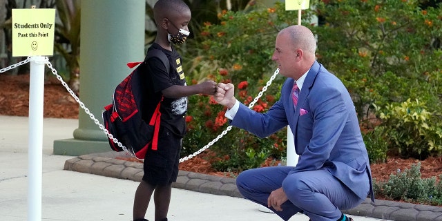 Addison Davis, Hillsborough County Superintendent of Schools, right, fist bumps student James Braden before he heads to class on the first day of school at Sessums Elementary School Tuesday, Aug. 10, 2021, in Riverview, Florida. Students are required to wear protective masks while in class unless their parents opt out. 