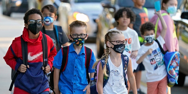 In this Tuesday, Aug.  10, 2021 file photo, Students, some wearing protective masks, arrive for the first day of school.