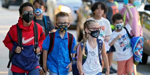 In this Tuesday, Aug. 10, 2021 file photo, Students, some wearing protective masks, arrive for the first day of school.